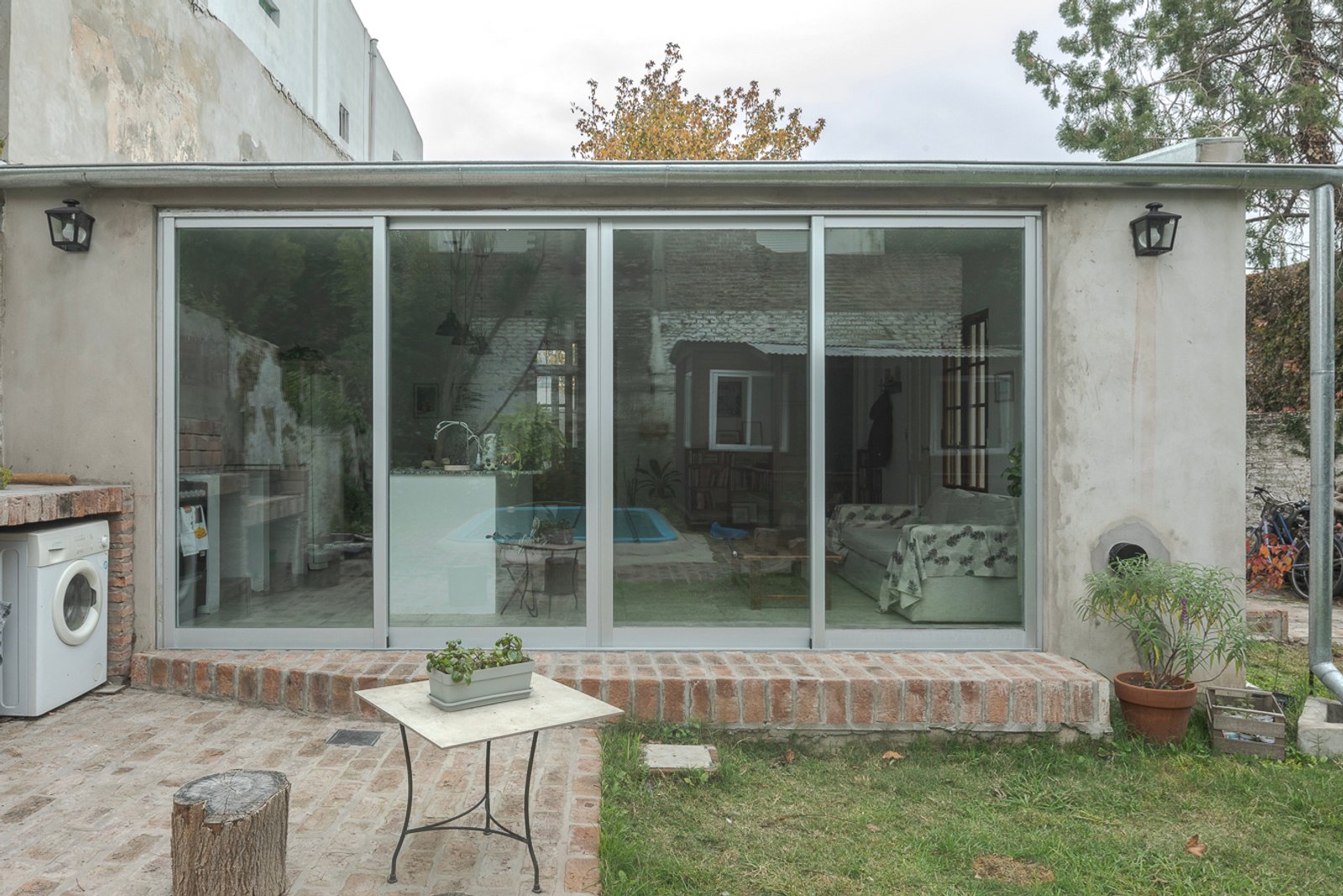 Fachada moderna con grandes ventanales de vidrio y patio — proyecto Reforma Navarro, por Estudio YME, en B1648 Tigre